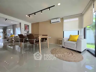 Spacious modern living room with dining area, featuring sleek furniture and large windows for natural light.