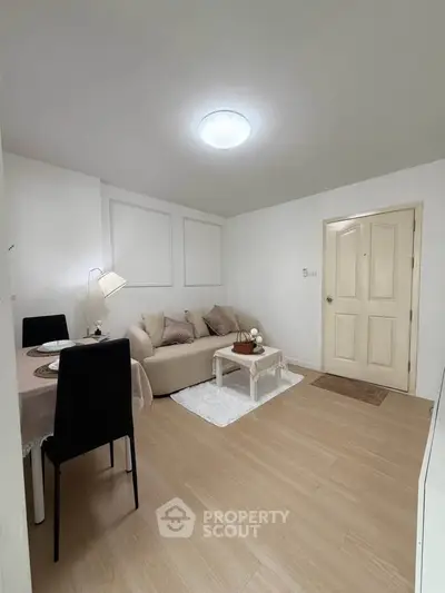 Cozy living room with modern decor and dining area, featuring a comfortable sofa and elegant lighting.