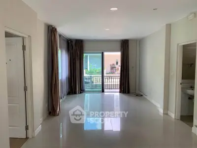 Spacious living room with large windows and balcony access, perfect for natural light and modern living.
