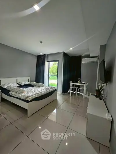 Modern bedroom with sleek design, featuring a comfortable bed, TV, and dining area, perfect for urban living.