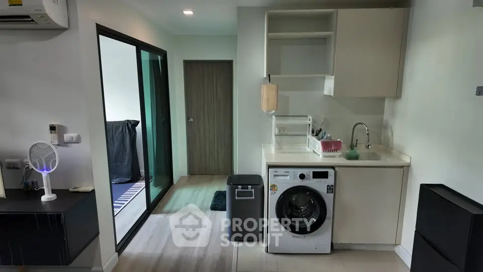 Modern apartment interior with compact kitchen and washing machine, featuring sleek design and efficient use of space.