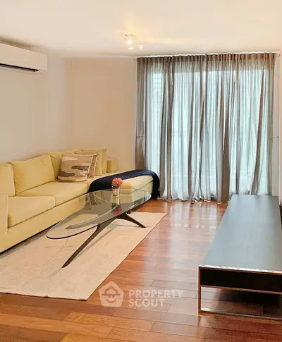 Modern living room with elegant decor, featuring a stylish sofa, glass coffee table, and floor-to-ceiling curtains.