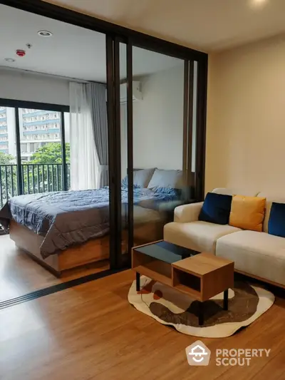 Modern studio apartment with cozy living area and bedroom, featuring a stylish glass partition and balcony view.