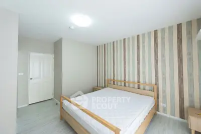 Modern minimalist bedroom with striped accent wall and wooden bed frame.