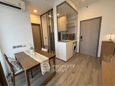 Modern apartment interior with dining area and compact kitchen featuring a washing machine.