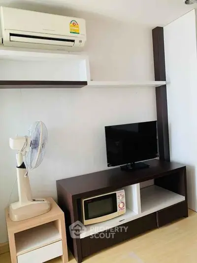 Modern living room with air conditioning, TV, and microwave on sleek furniture.