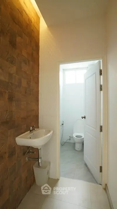 Modern bathroom with wooden accent wall and white fixtures