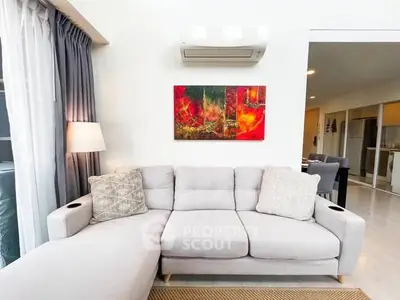 Modern living room with stylish sofa and vibrant artwork, featuring open layout and natural light.