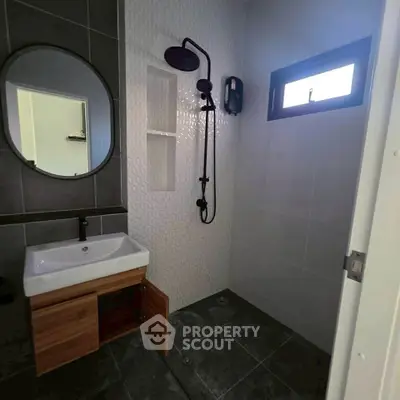Modern bathroom with sleek fixtures and stylish tile design, featuring a round mirror and spacious shower area.