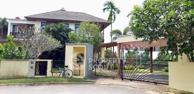 Luxurious modern villa with lush garden and spacious driveway in tropical setting.