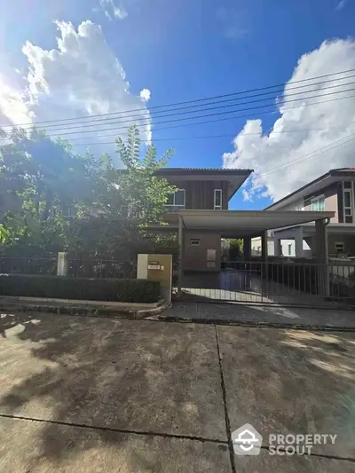 Modern two-story house with spacious driveway and lush greenery under a clear blue sky.