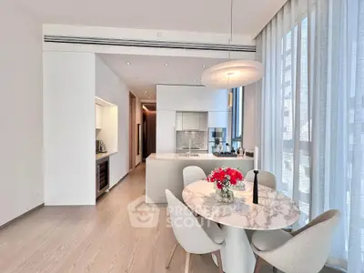 Modern kitchen with open layout and elegant dining area featuring marble table and contemporary lighting.