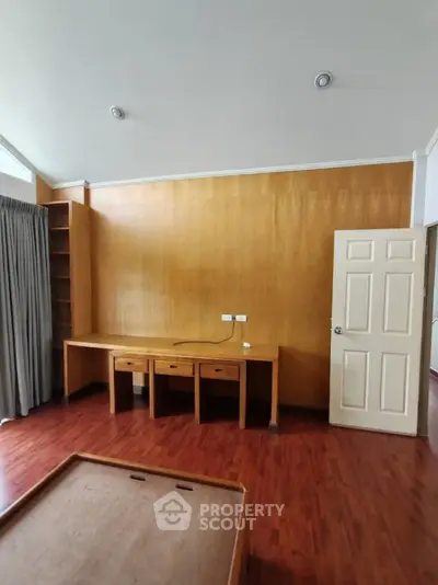 Spacious room with wooden flooring and built-in desk, ideal for home office setup.