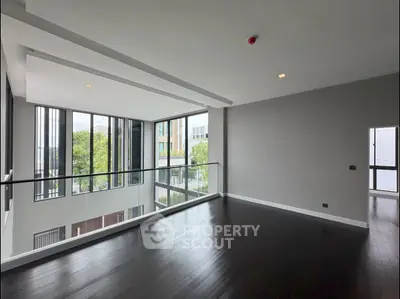 Spacious modern living room with large windows and dark wood flooring.