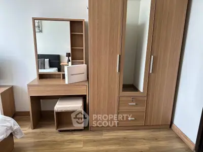 Modern bedroom with wooden wardrobe and vanity set, showcasing sleek design and ample storage.