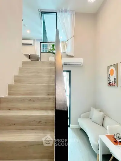 Modern duplex interior with stylish staircase and cozy living area, featuring elegant decor and natural light.