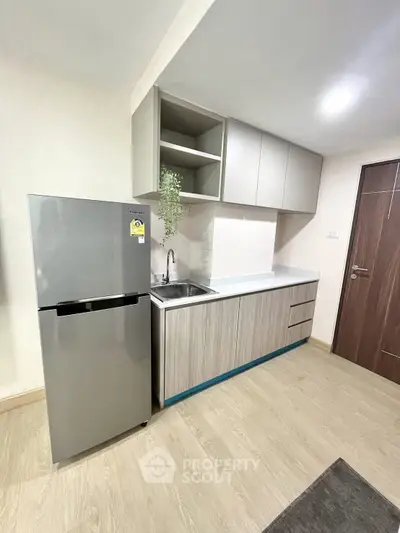 Modern kitchen with sleek cabinetry and stainless steel fridge in a stylish apartment.