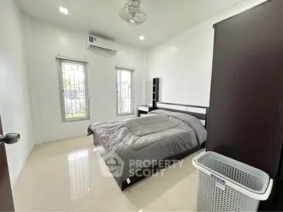 Modern bedroom with sleek furniture and natural light, featuring air conditioning and minimalist design.