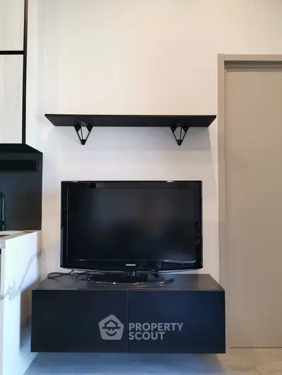 Modern living room with sleek black TV stand and wall-mounted shelf, perfect for minimalist decor.