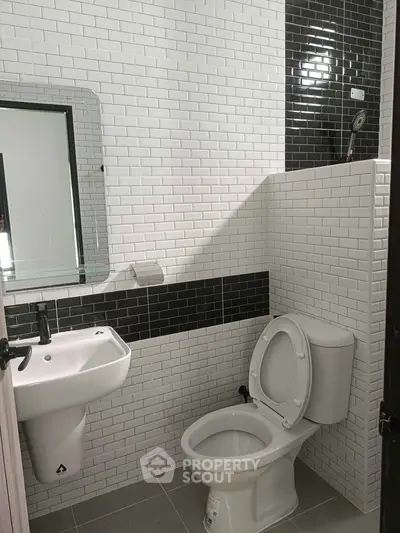 Modern bathroom with sleek black and white tile design and contemporary fixtures.