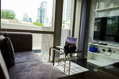 Modern living room with large window and city view, featuring a cozy sofa and sleek TV setup.