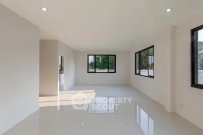 Spacious modern living room with large windows and glossy floors, offering abundant natural light and serene views.