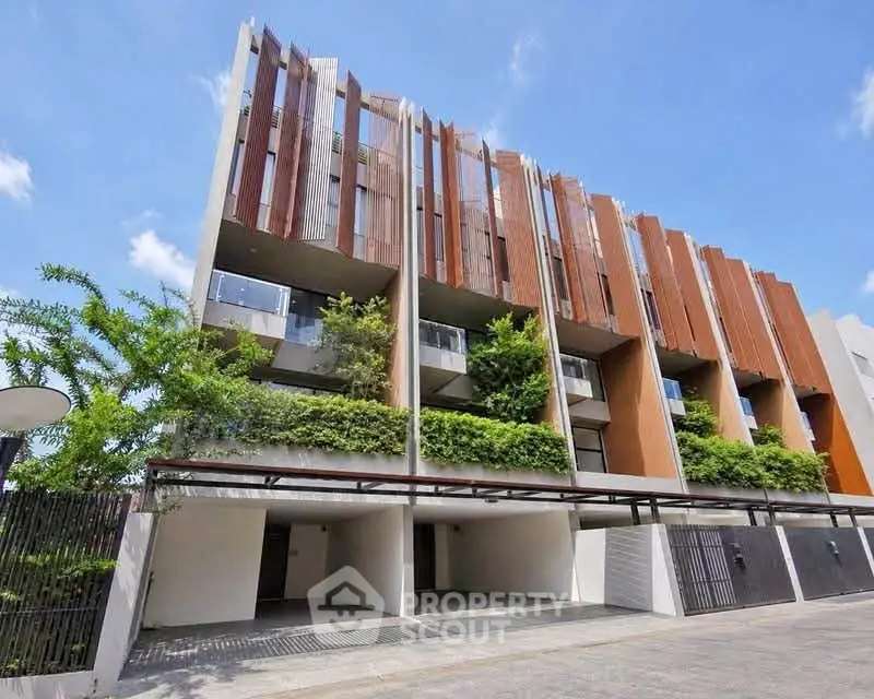 Modern architectural townhouse with lush greenery and spacious balconies.