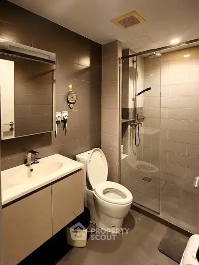 Modern bathroom with glass shower and sleek fixtures in contemporary home.