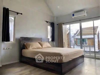 Spacious bedroom with modern decor and large windows offering natural light.