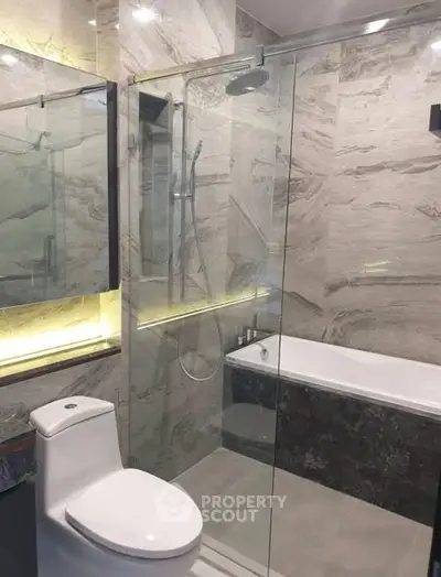 Luxurious modern bathroom with glass shower and elegant marble finishes.