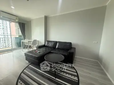 Modern living room with sleek black sofa and stylish decor in a high-rise apartment.