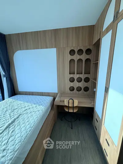 Modern bedroom with built-in wooden furniture and large window for natural light.