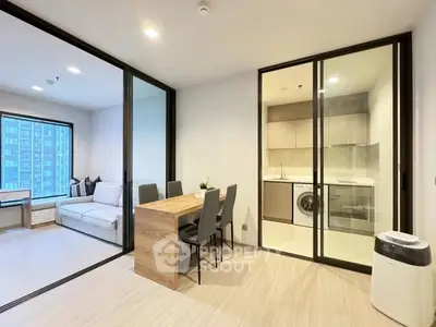 Modern apartment with glass partitions, cozy living area, and compact kitchen featuring a washing machine.