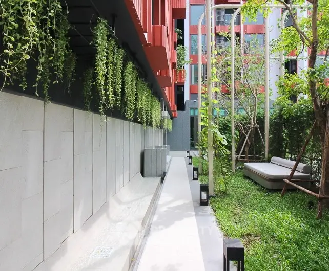 Modern garden area with lush greenery and stylish outdoor seating in urban residential complex.