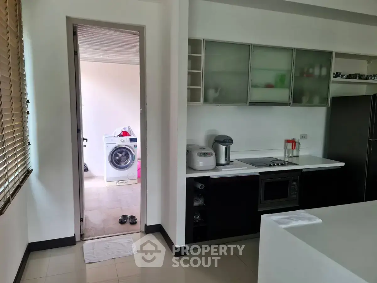Modern kitchen with sleek appliances and adjacent laundry area in a stylish home.