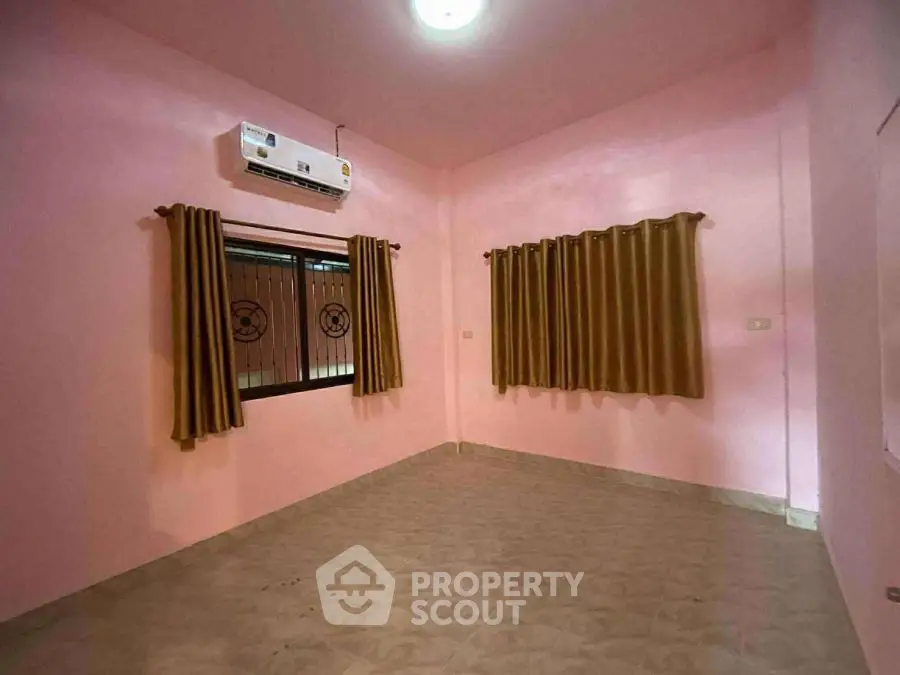 Spacious empty room with pink walls and air conditioning, ready for customization.