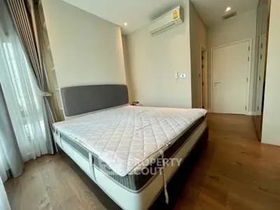 Spacious bedroom with modern design and natural light, featuring a comfortable bed and elegant wooden flooring.