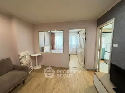 Cozy living room with modern decor and open view to adjacent rooms, featuring stylish furniture and wooden flooring.