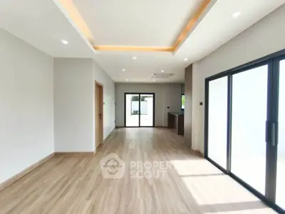 Spacious modern living room with wooden flooring and large sliding glass doors.