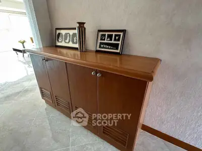 Elegant wooden cabinet in a stylish living room with decorative accents and framed photos.