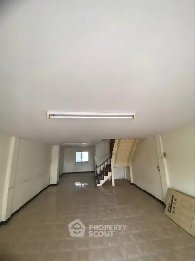 Spacious interior with tiled flooring and staircase, ideal for customization.