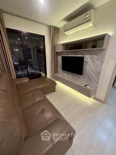 Modern living room with leather sofa, wall-mounted TV, and city view through large window.