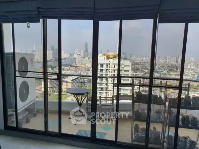 Stunning cityscape view from a modern balcony with glass doors and outdoor seating.