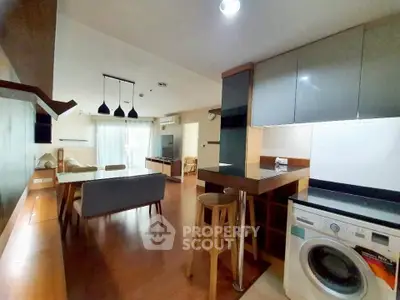 Modern open-plan kitchen and living area with washing machine and stylish decor.