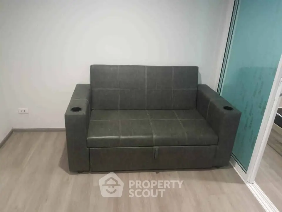 Modern compact living room with sleek dark sofa and minimalist design.