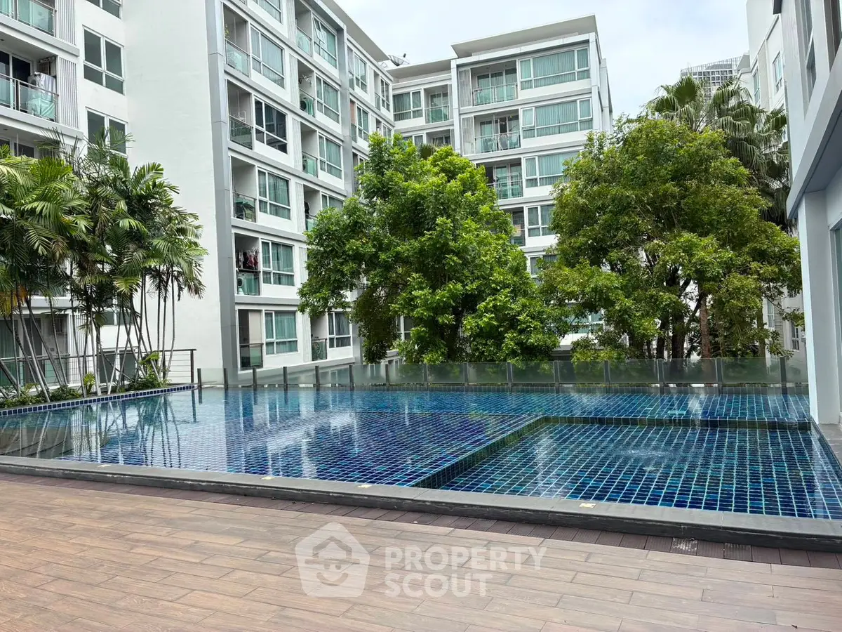 Modern apartment complex with a serene outdoor pool and lush greenery.