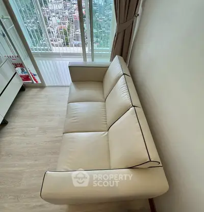 Modern living room with sleek leather sofa and city view balcony.