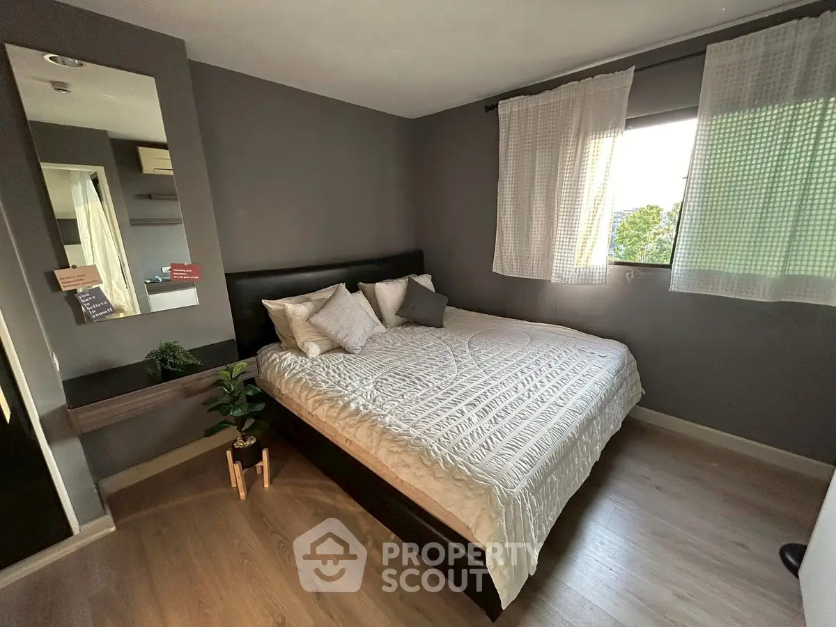 Cozy bedroom with modern decor and large window offering natural light.