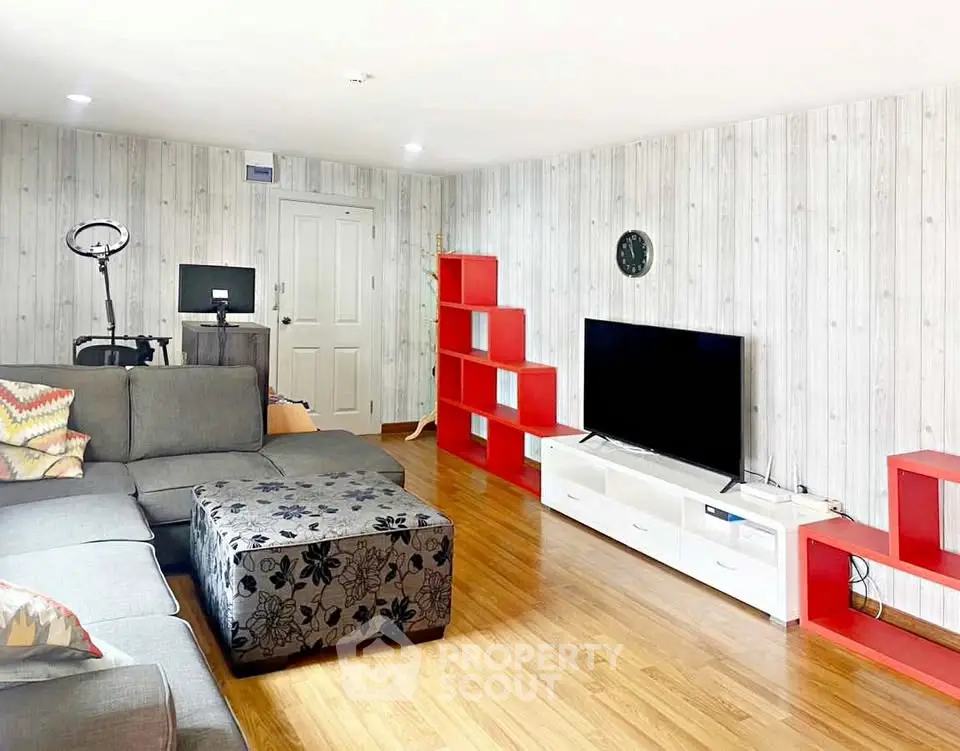 Spacious living room with modern decor and vibrant red shelving units.
