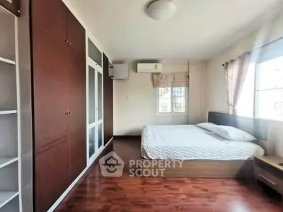 Spacious bedroom with wooden flooring and built-in wardrobe in modern apartment.